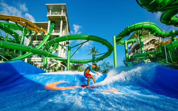 Boy surfing on Flow Rider at Waterbom Bali water park, Indonesia.