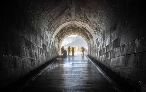 Visitors in yellow ponchos exiting a tunnel towards Niagara Falls on a New York to Niagara Falls tour.