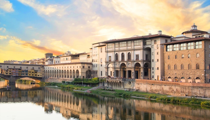 Golden sunset over the Uffizi Gallery, viewed from across the Arno River, reflecting the gallery's grandeur and the tranquility of Florence