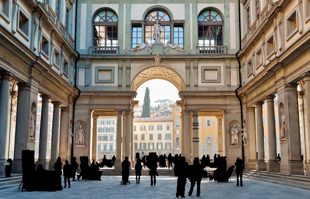 Visitors in the serene courtyard of the Uffizi Gallery on a quiet weekday, with the architectural grandeur and statues basking in the Florence sunlight