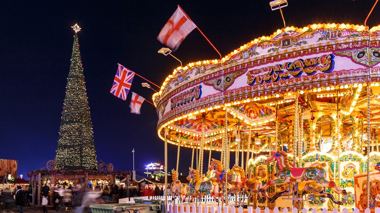 Hyde Park Winter Wonderland carousel and Christmas tree in London at night.