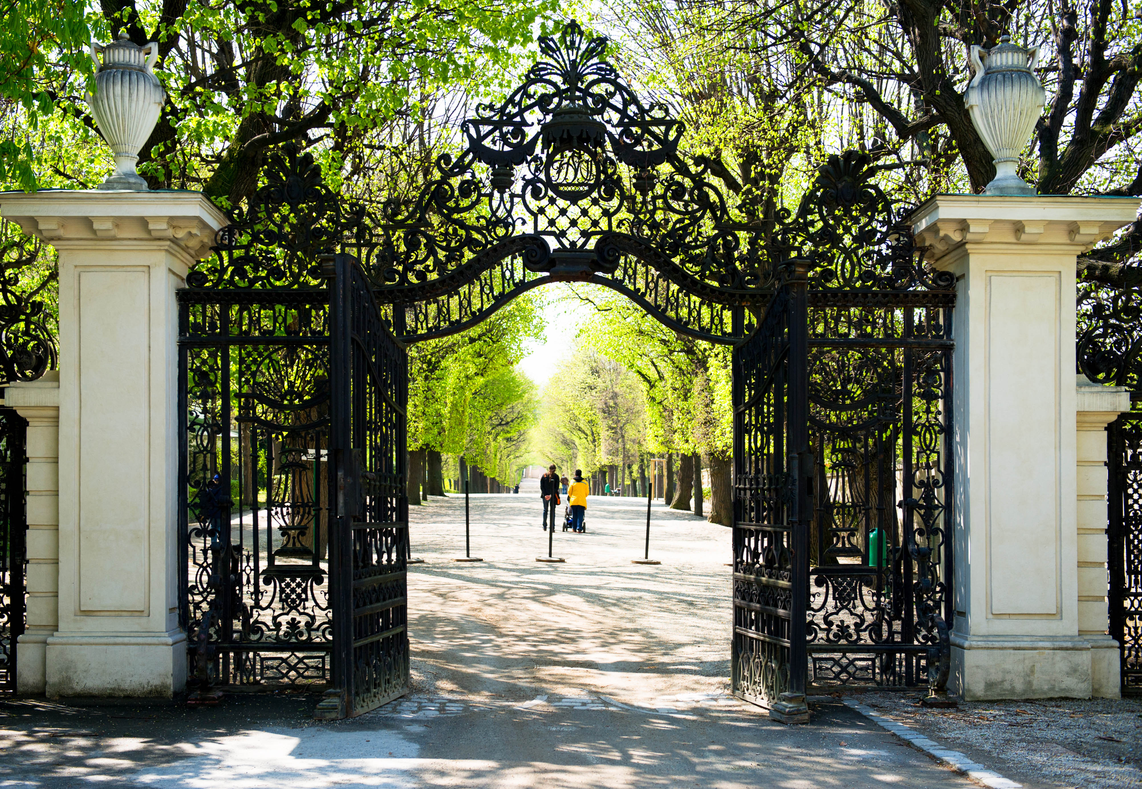 Schonbrunn Palace ornate garden gate with tree-lined path in Vienna.