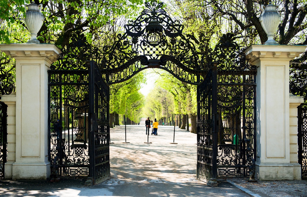 Schonbrunn Palace ornate garden gate with tree-lined path in Vienna.
