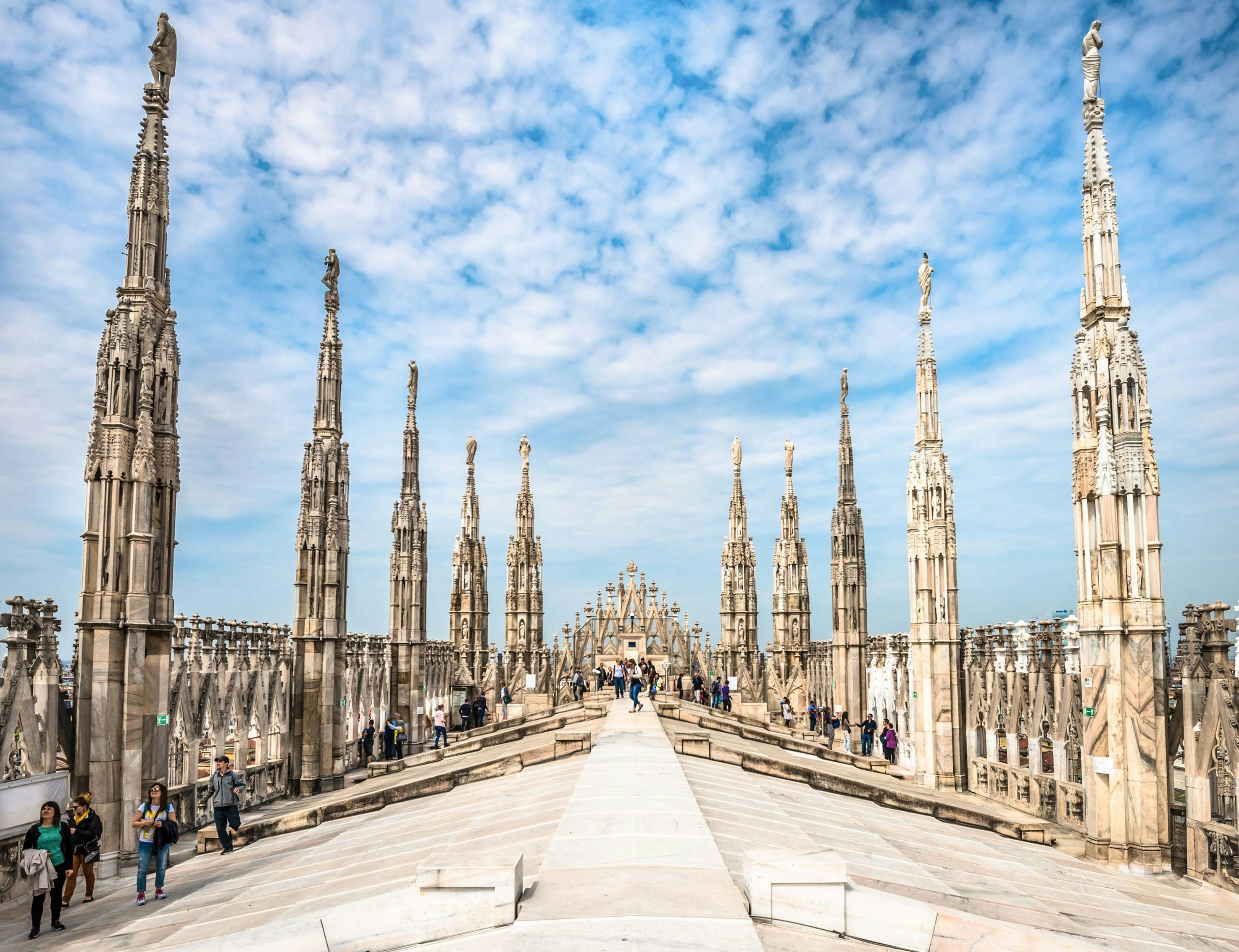 Duomo di Milano facade with tourists exploring the cathedral in Milan, Italy.
