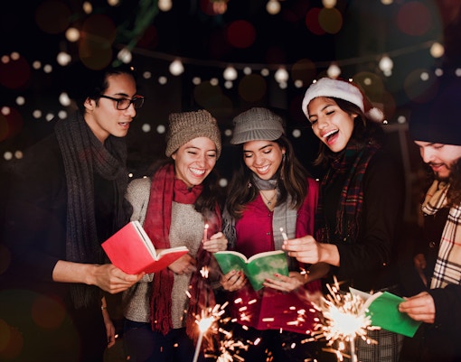 Group singing Christmas carols with sparklers in London.