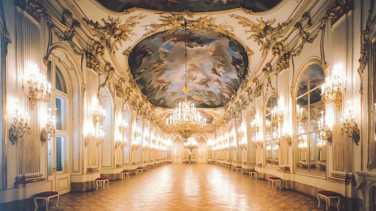 Schonbrunn Palace grand hall with ornate chandeliers and detailed ceiling fresco.