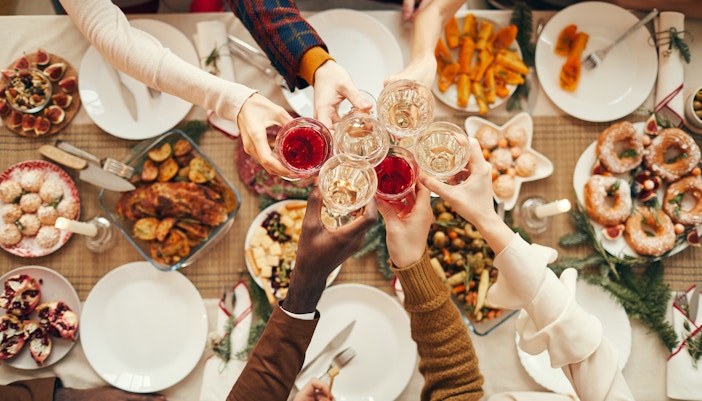 Toasting at a festive dinner table on New Year's Eve with various dishes.