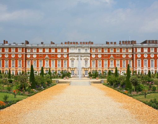 Tourists exploring the magnificent Baroque architecture of Hampton Court Palace on a sunny day
