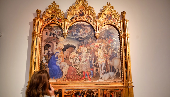 Visitor looking at the elaborate Adoration of the Magi altarpiece, a mesmerizing example of Florence's Uffizi Gallery treasures.