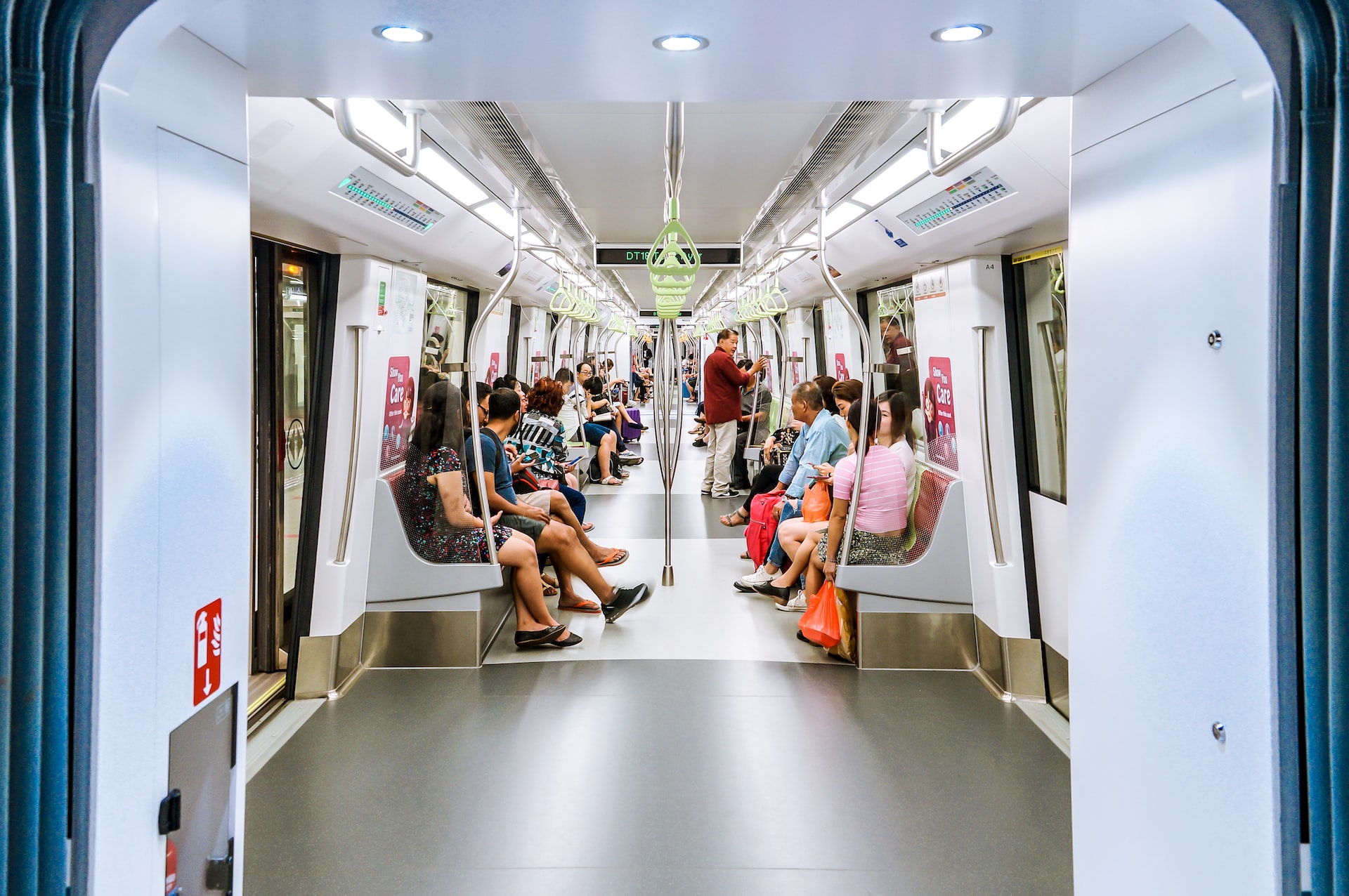 Singapore metro train arriving at a modern station platform with passengers waiting to board.