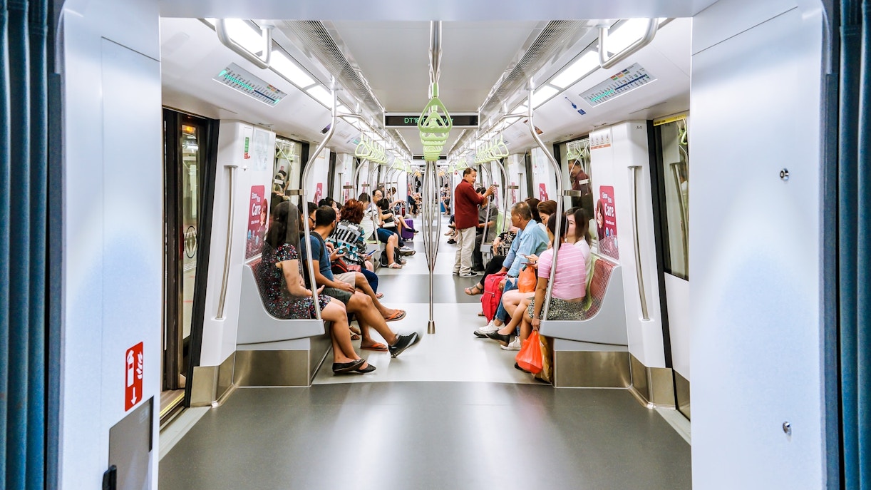 Singapore metro train arriving at a modern station platform with passengers waiting to board.