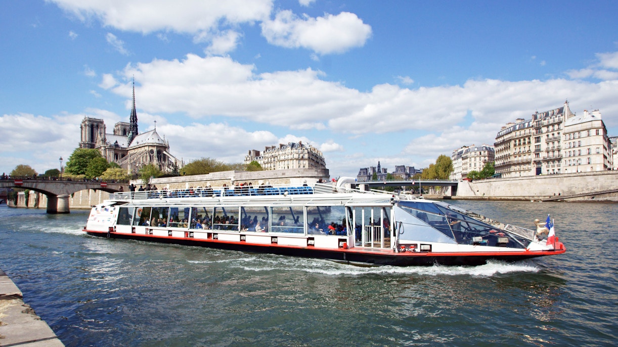 Bateaux Mouches boat cruising on the Seine River in Paris, passing by the Eiffel Tower.
