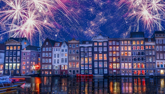 Fireworks over Amsterdam canal houses during New Year celebration.