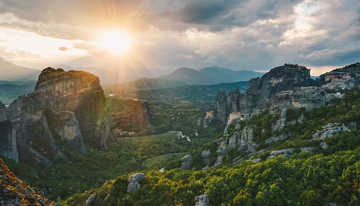 Meteora rock formations at sunset, Greece, highlighting hiking trails.