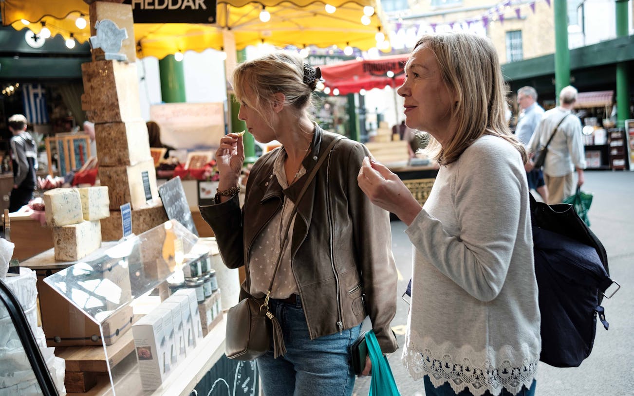 Visitors sampling cheese at a market stall during a London food tour.