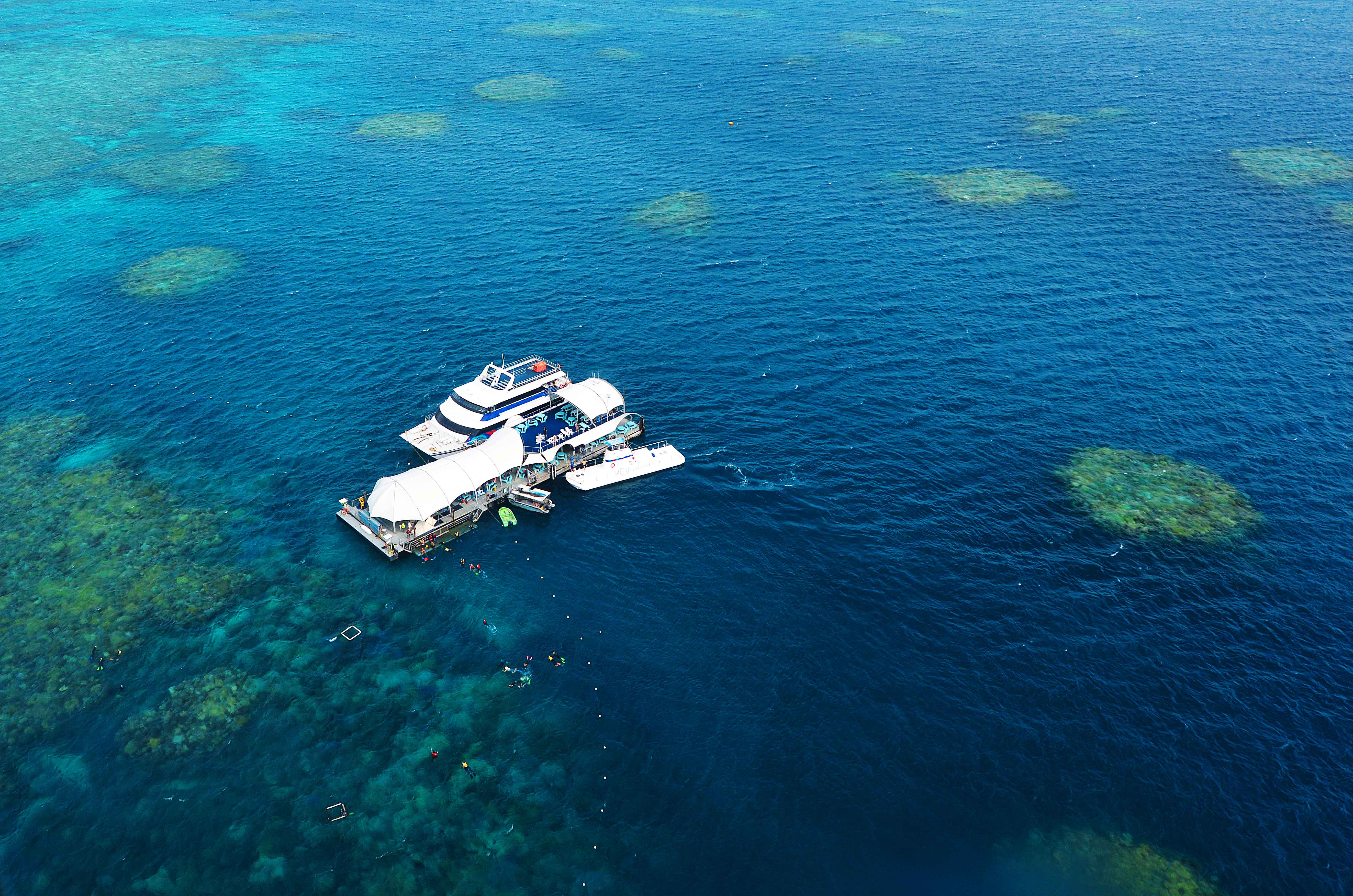 Cruise boat at Moore Reef, Great Barrier Reef, with snorkelers exploring coral formations.