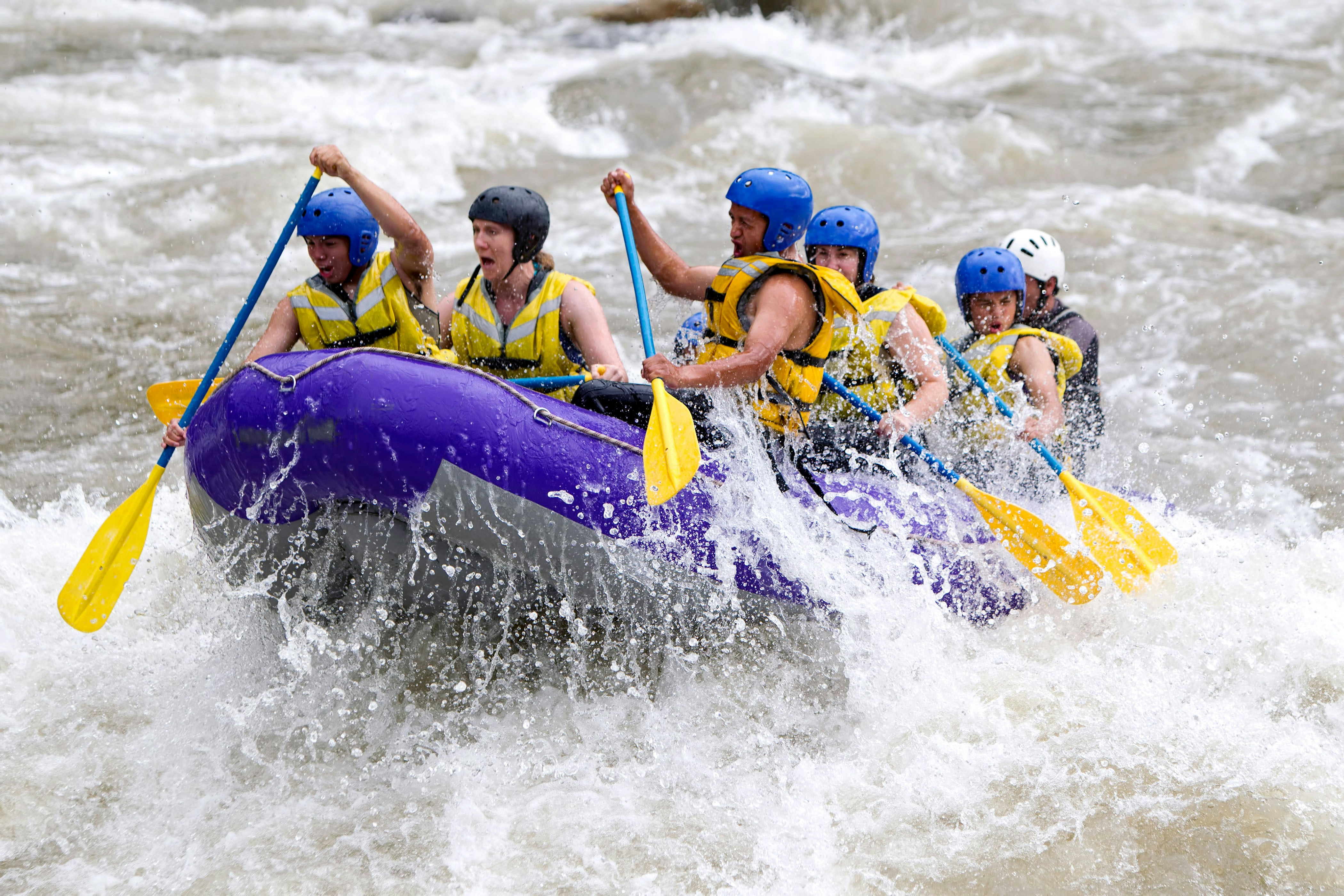Group river rafting in Interlaken, navigating rapids with paddles.