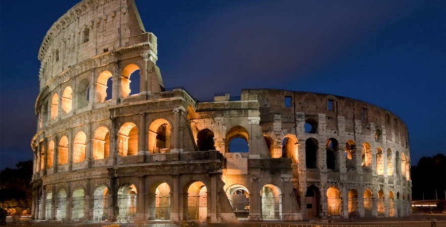 Colosseum illuminated at night in Rome, Italy, showcasing its ancient architecture.