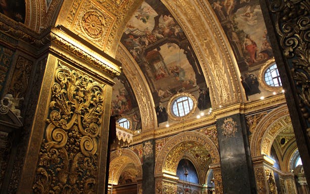 Ornate interior of the Archbasilica of St. John Lateran, featuring detailed gold carvings and frescoed ceilings.