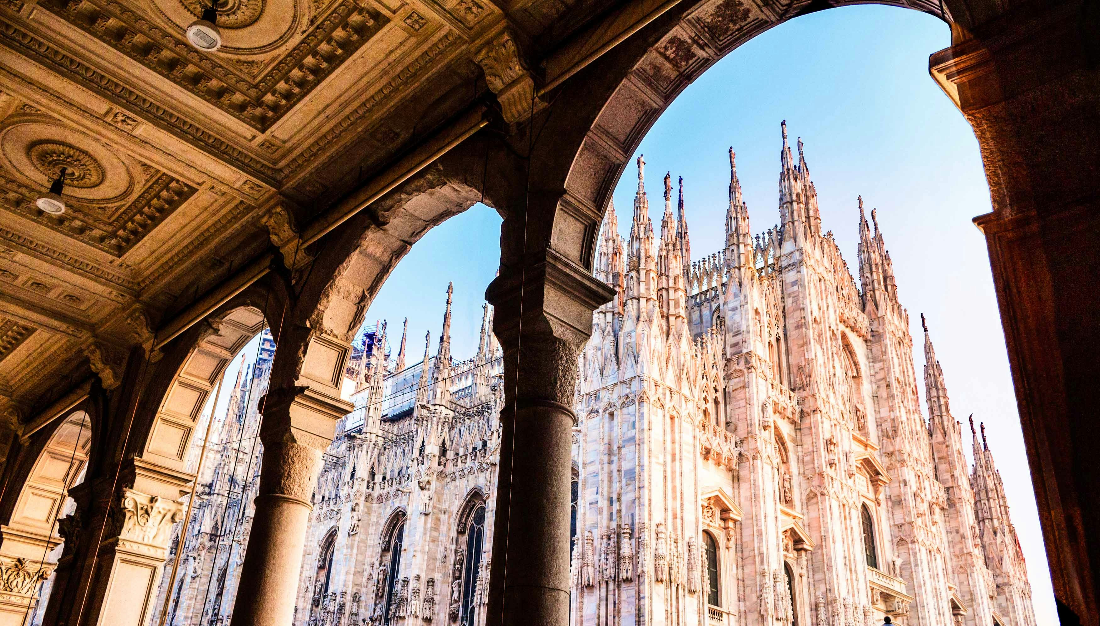 Duomo di Milano facade with tourists exploring the cathedral in Milan, Italy.
