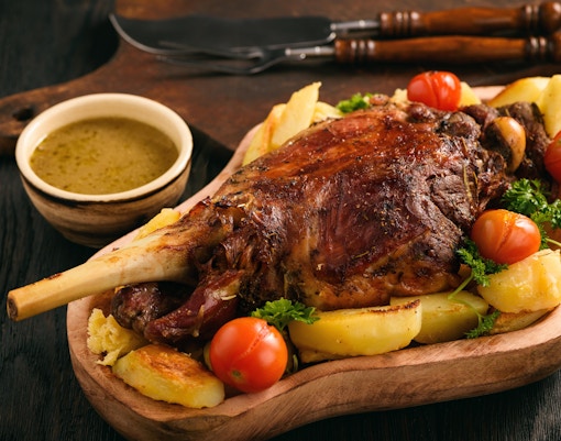 Slow baked lamb leg with potatoes and sauce.