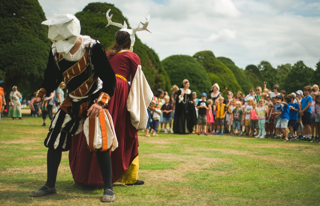 Medieval reenactment at Hampton Court Palace, London, with performers in costume and a crowd watching.