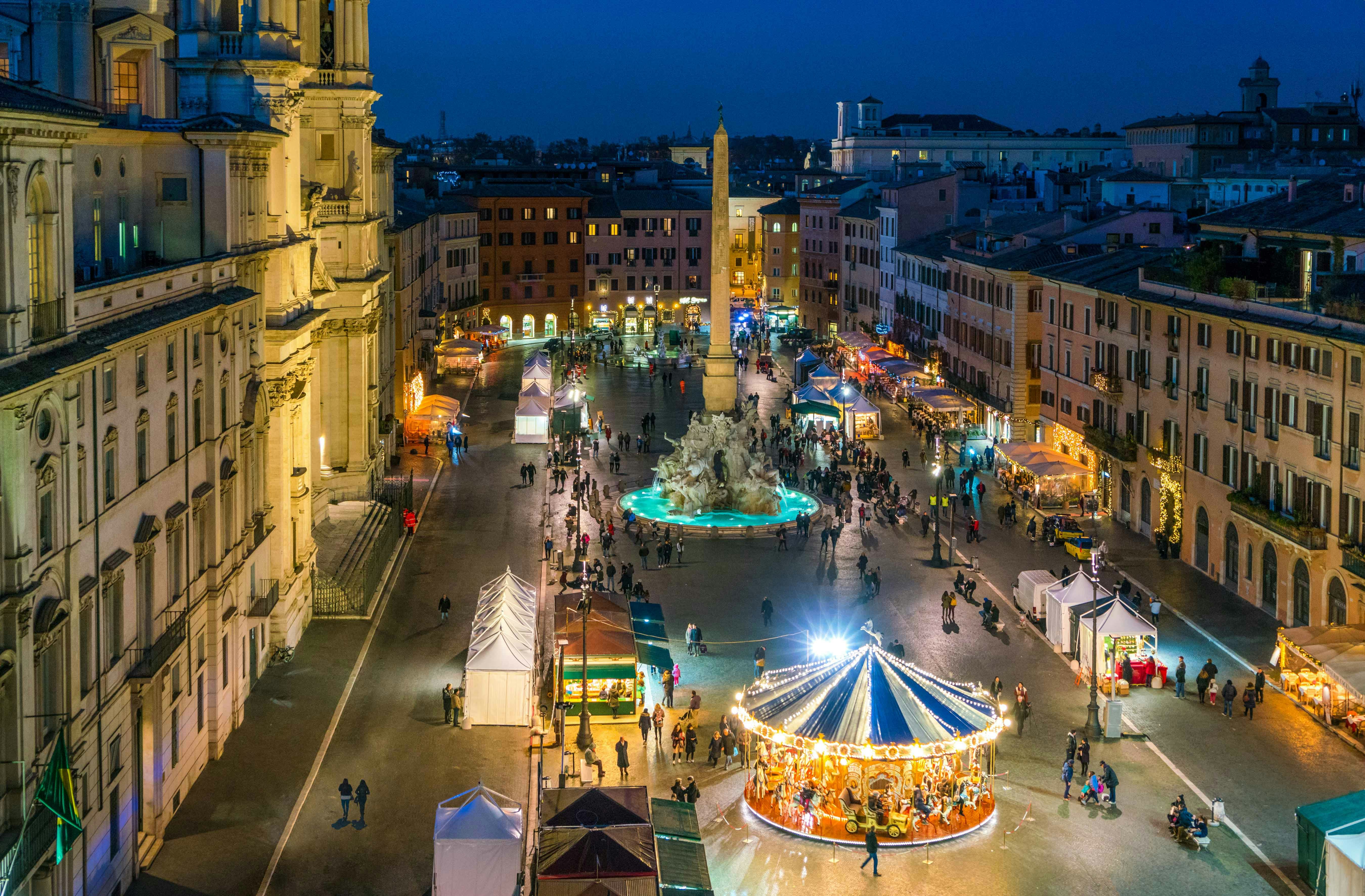 Christmas market in Piazza Navona, Rome, with a carousel and festive lights.