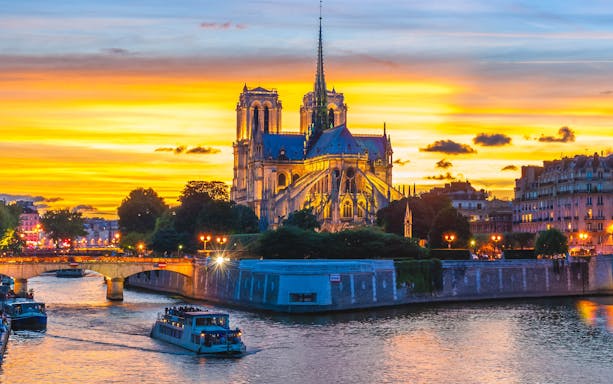 Seine River cruise at night with Notre-Dame Cathedral illuminated in Paris.