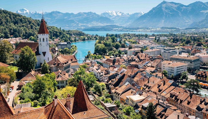 Paragliders soaring over Interlaken with views of Swiss Alps and Lake Thun.