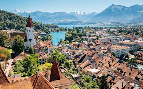 Aerial view of Interlaken with historic buildings, church, and mountains in the background.