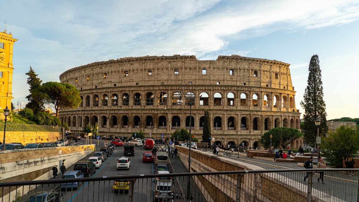 Colosseum's outer ring with arches and surrounding street in Rome, Italy.
