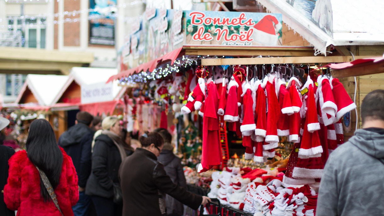 Paris Christmas market stall with Santa costumes and festive shoppers.