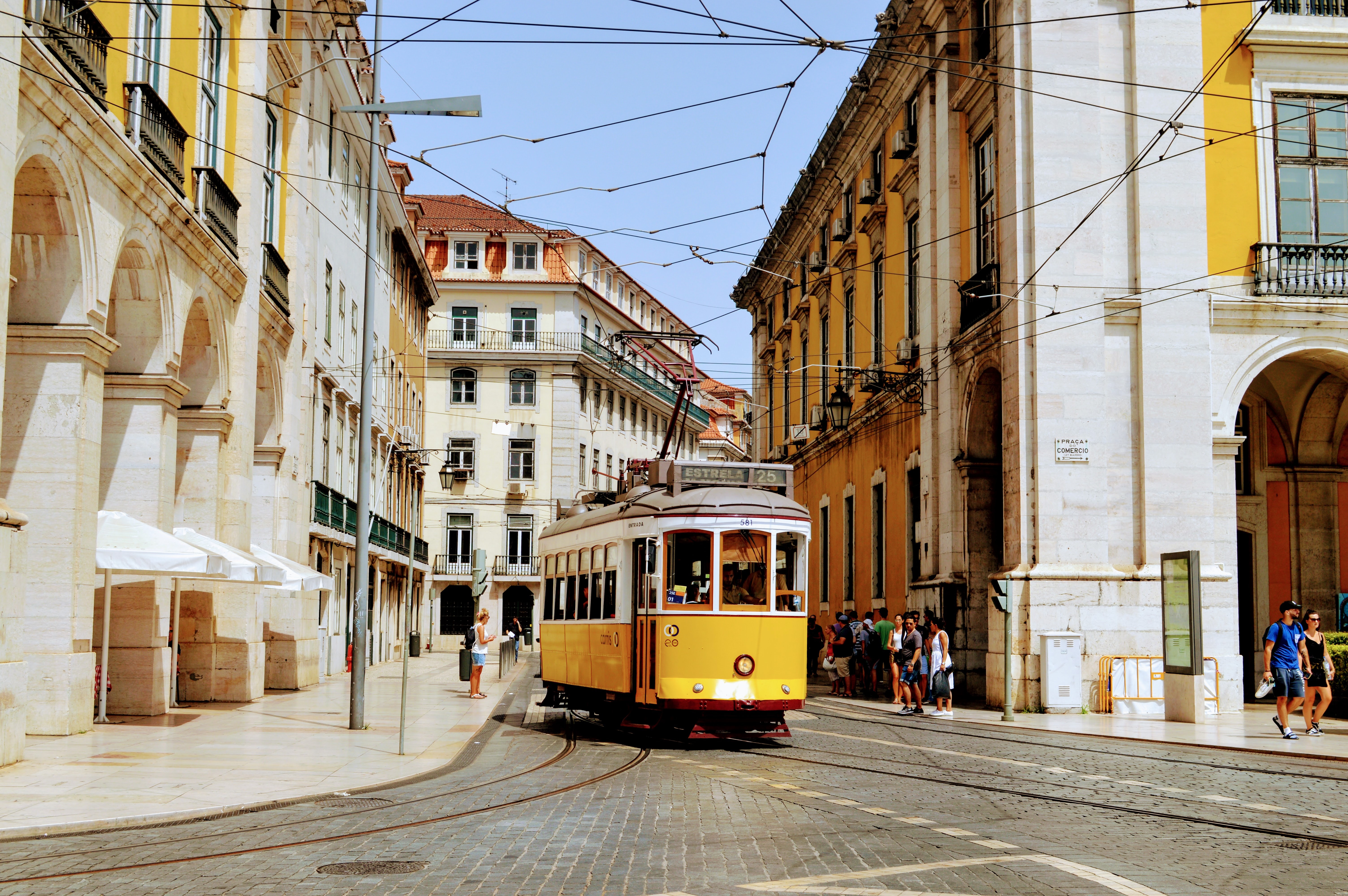 Lisbon tram passing through historic Alfama district with cobblestone streets and colorful buildings.