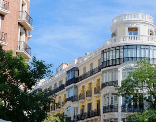 Historic architecture on Fuencarral Street, Madrid, with ornate balconies and trees.