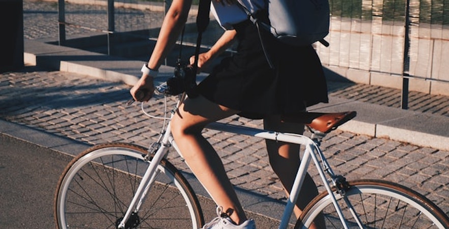 Cyclist riding on a city path with a backpack.