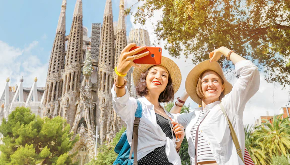 Tourists taking a selfie in front of Sagrada Familia towers in Barcelona.