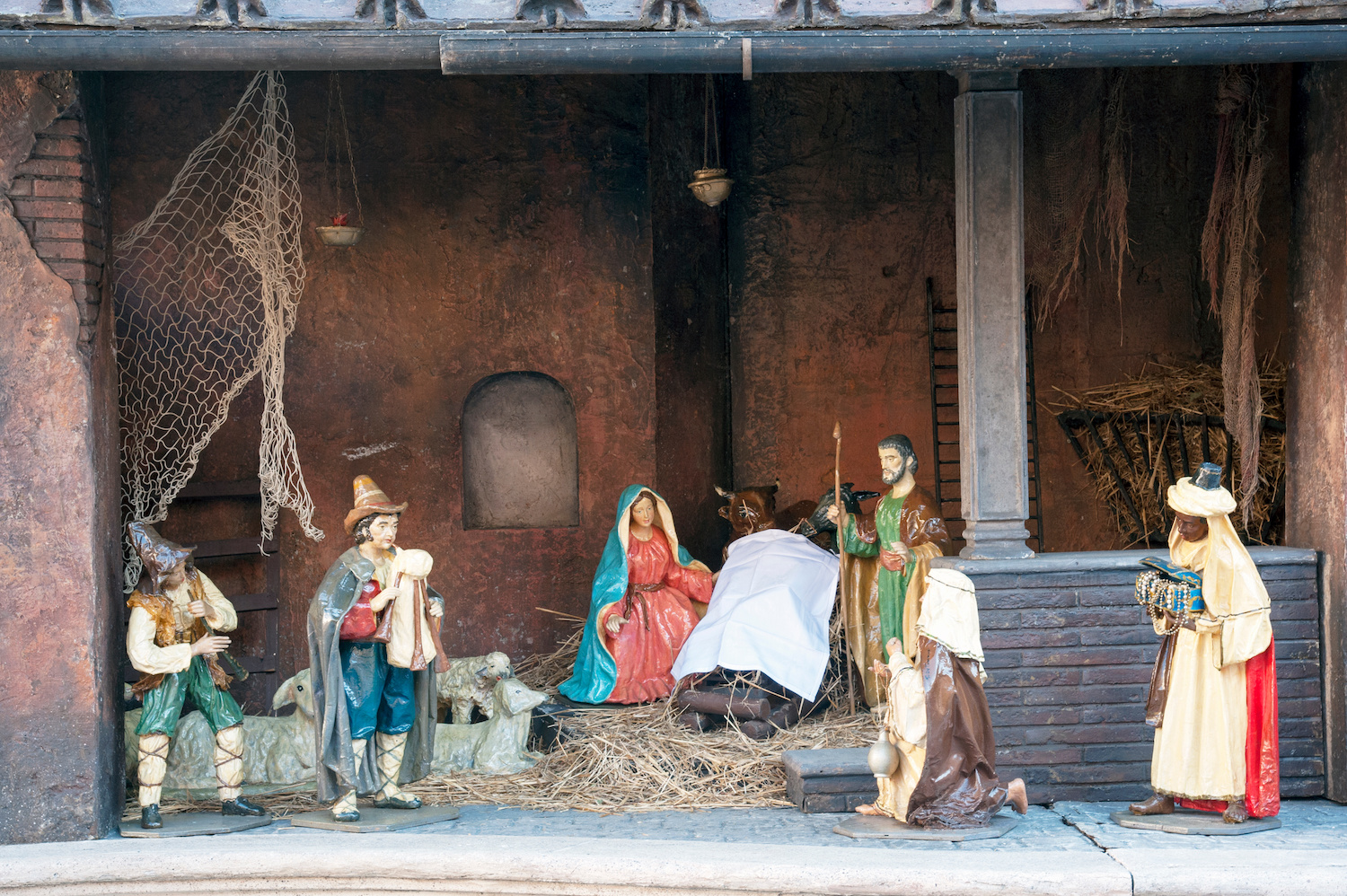 Nativity scene display in Rome during winter, featuring figures of Mary, Joseph, and the Magi.