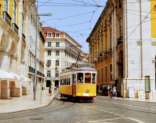 Lisbon's iconic yellow Tram 28 navigating through historic Alfama district streets.