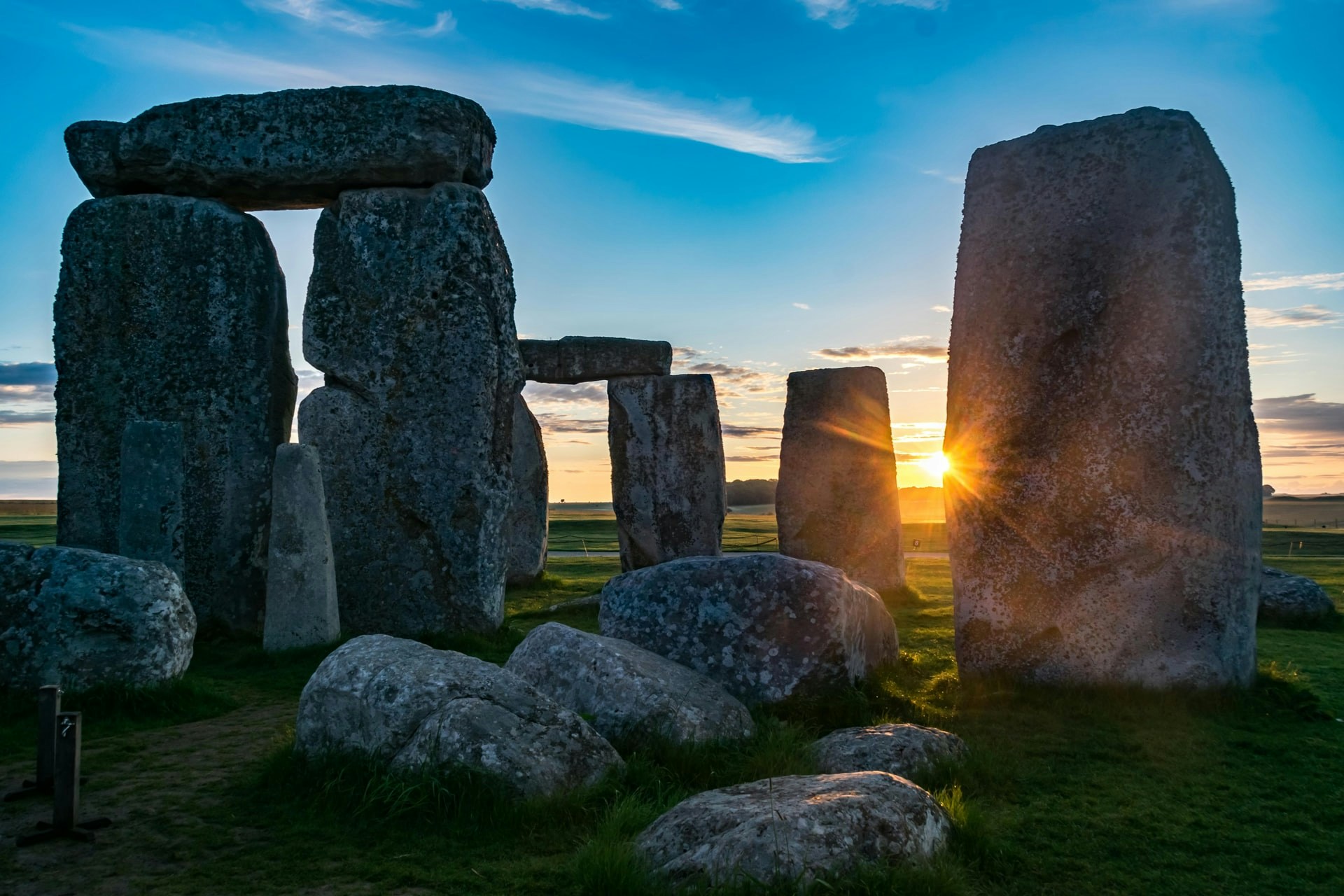 Stonehenge at sunrise with sun rays peeking through ancient stone structures.