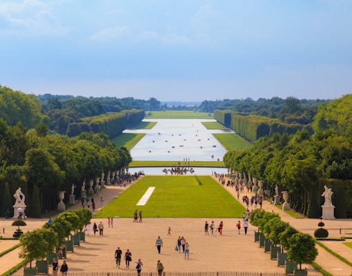 Gardens of Versailles with manicured lawns, fountains, and sculptures in Versailles, France.