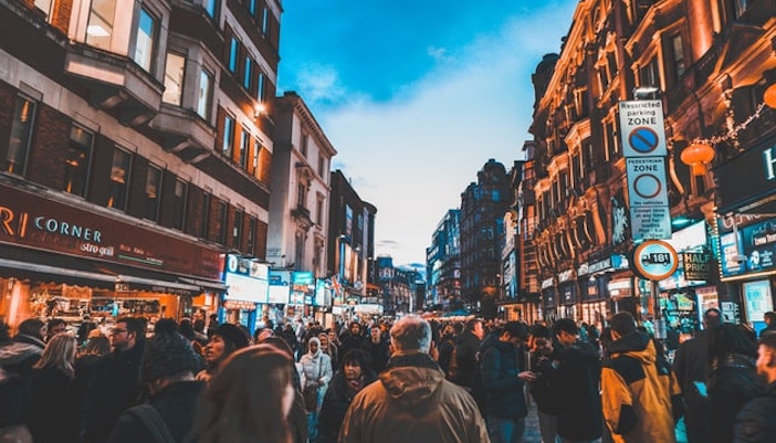 Crowded Leicester Square street scene in London with illuminated signs and historic buildings.