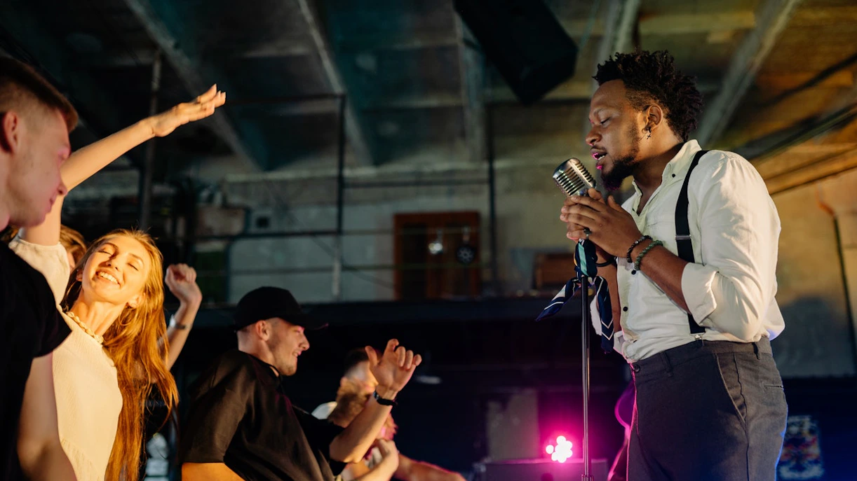 Performer singing at Barcelona Jazz Festival with audience dancing nearby.