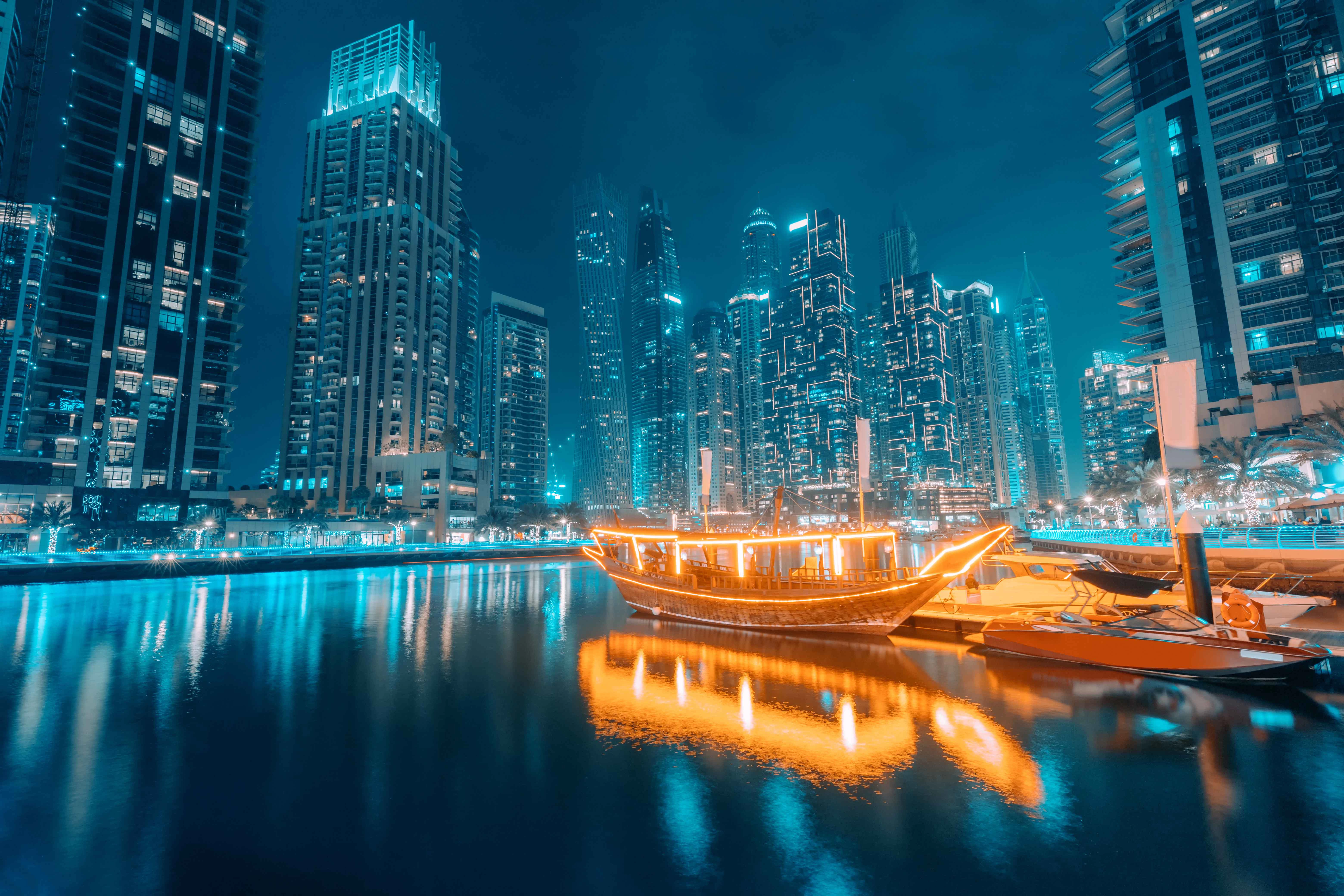 Dhow cruise on Dubai Marina with illuminated skyscrapers at night.