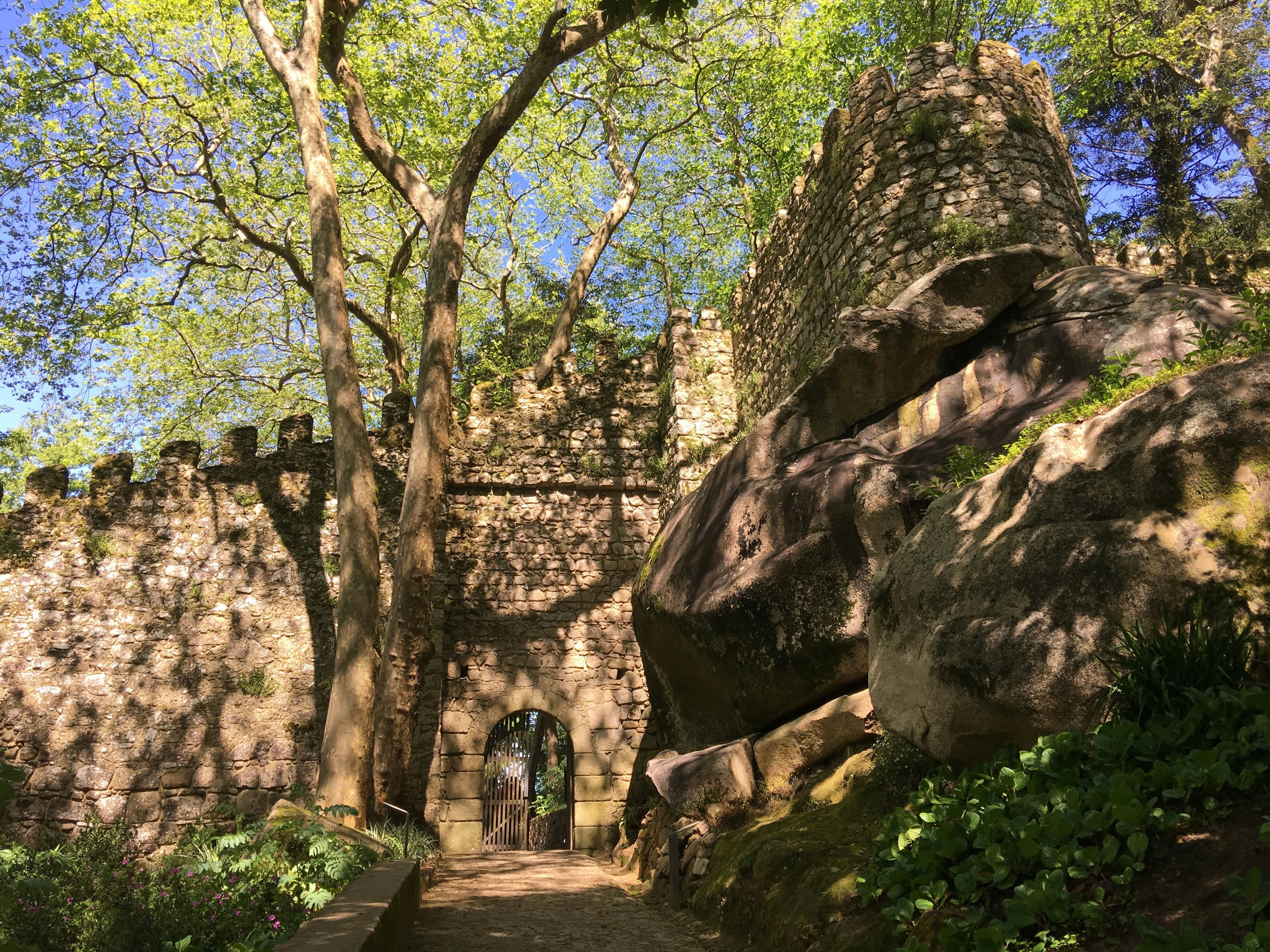 Moorish castle wall and gate surrounded by trees in Sintra, Portugal.