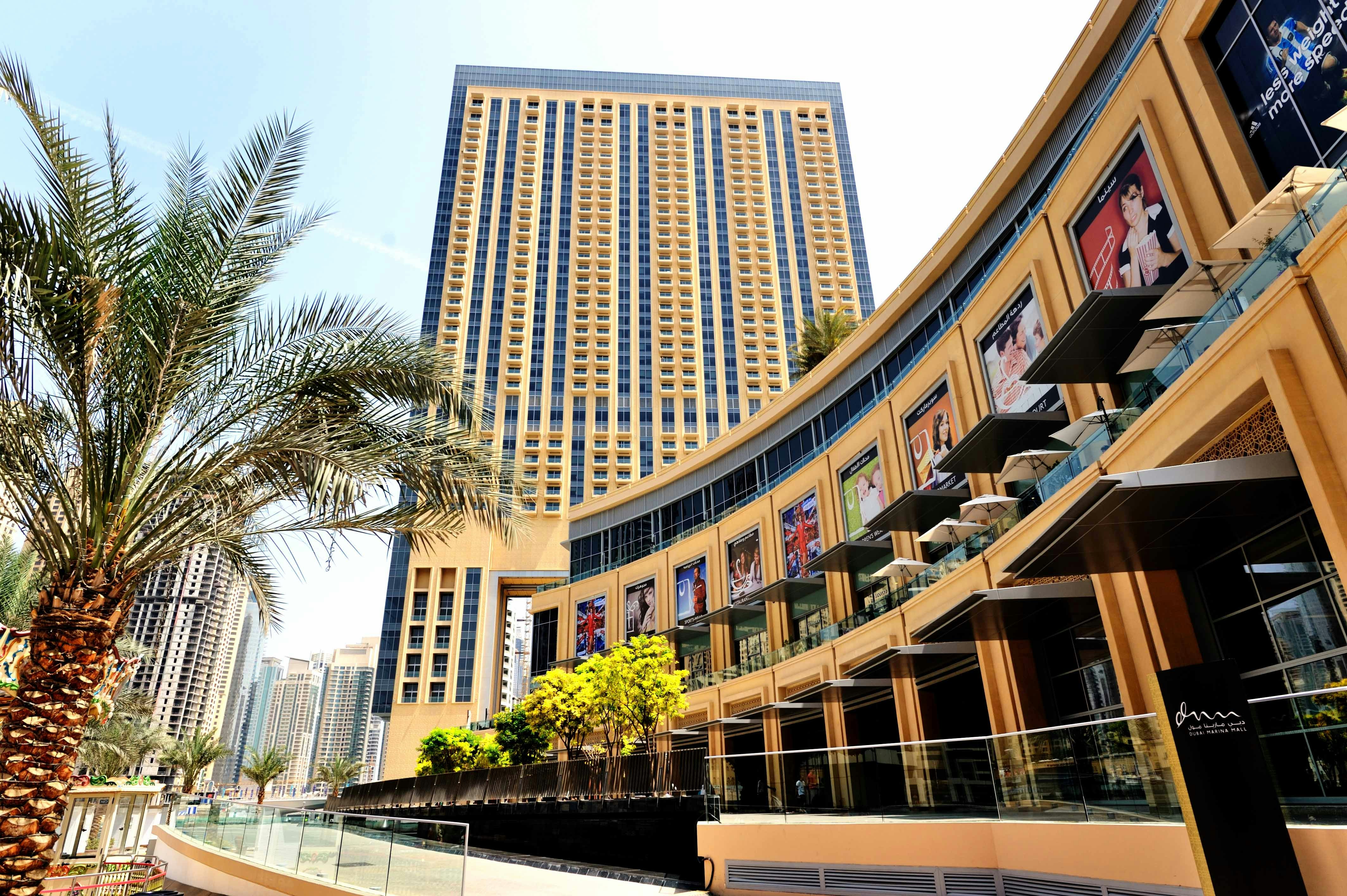 Dubai Marina Mall exterior with palm trees and high-rise buildings in the background.