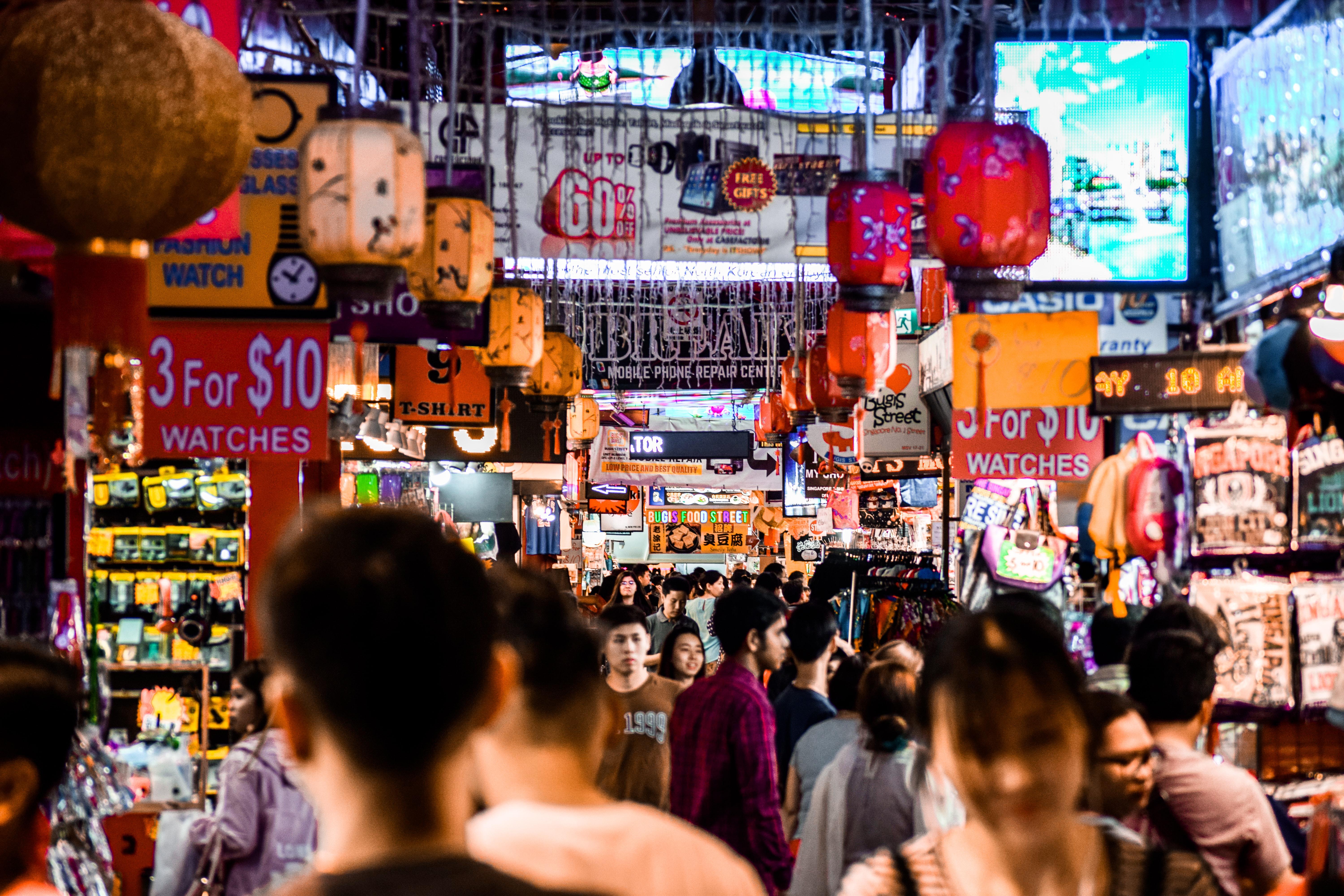 Bugis+ Singapore shopping mall exterior with colorful lights and bustling street scene.