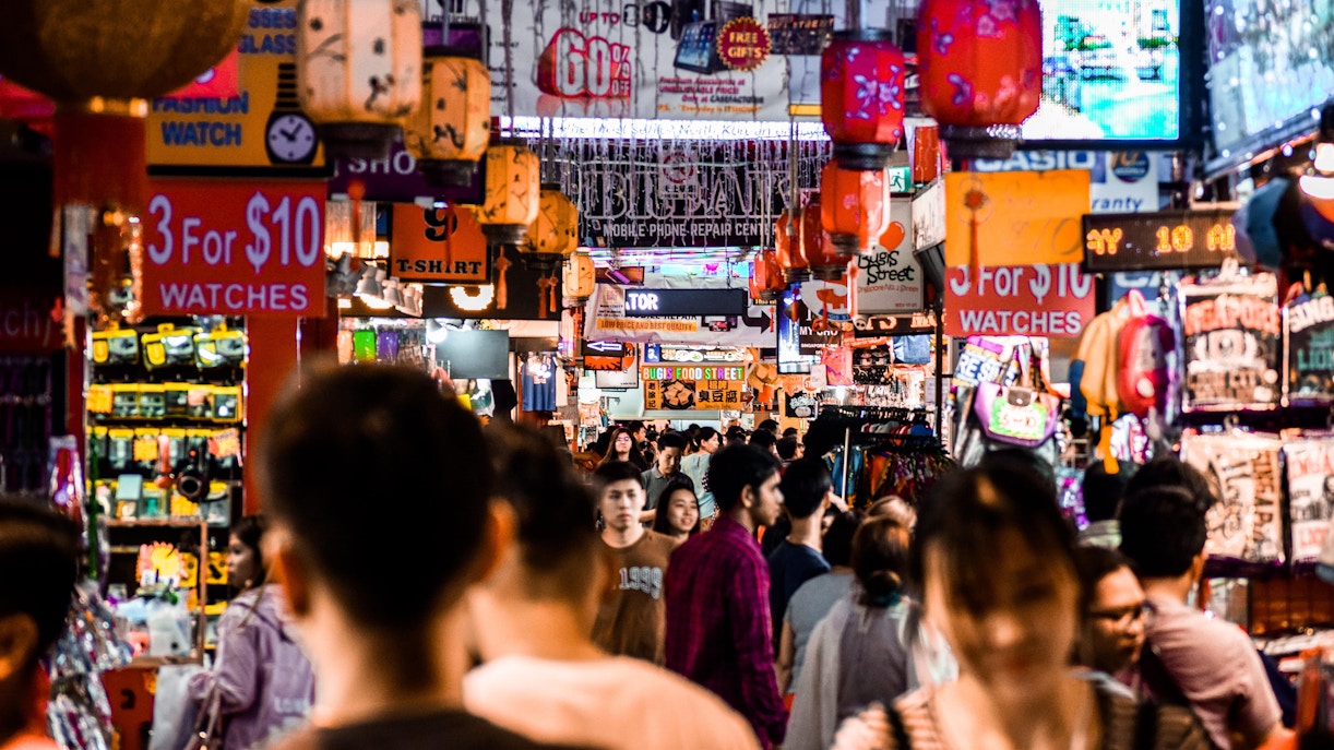 Bugis+ Singapore shopping mall exterior with colorful lights and bustling street scene.