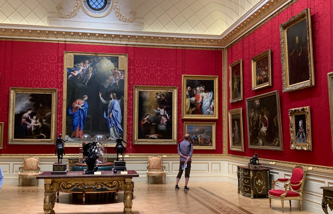 Visitor admiring the rich collection of Baroque paintings in the opulent red rooms of the Uffizi Gallery during a half-day visit in Florence