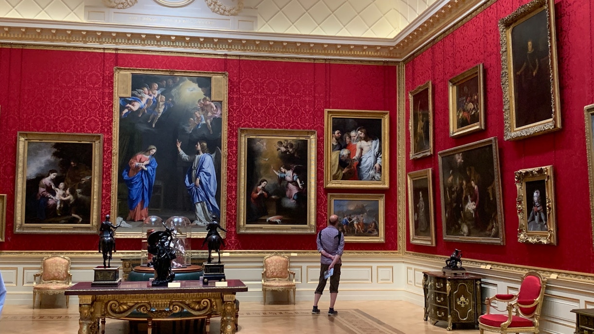 Visitor contemplates the classical art collection in the red-walled room of Uffizi Gallery, showcasing the rich history and grandeur on display