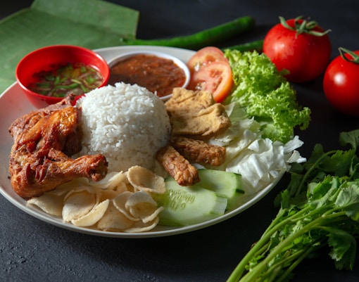 Nasi Lemak served on a banana leaf with sambal, egg, and anchovies, Singapore street food.